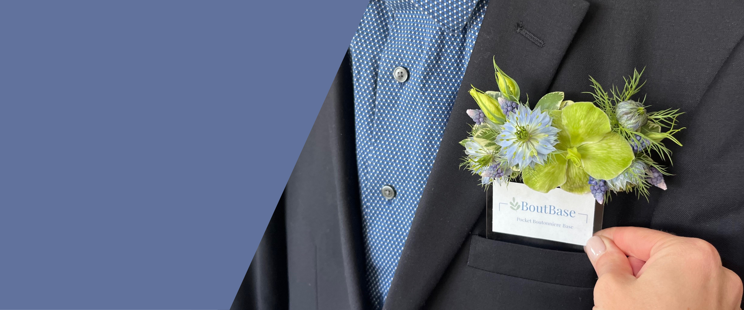 Person wearing a dark suit with a blue shirt and a pocket floral boutonniere sliding into the suit pocket. 